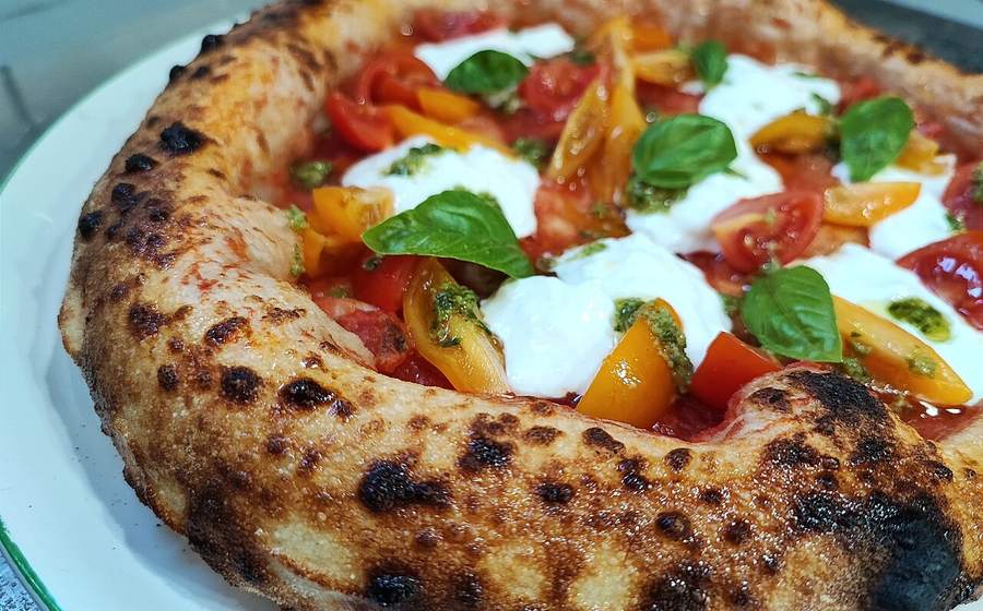Leopard-spotted Neapolitan pizza with mozzarella, tomatoes and basil
